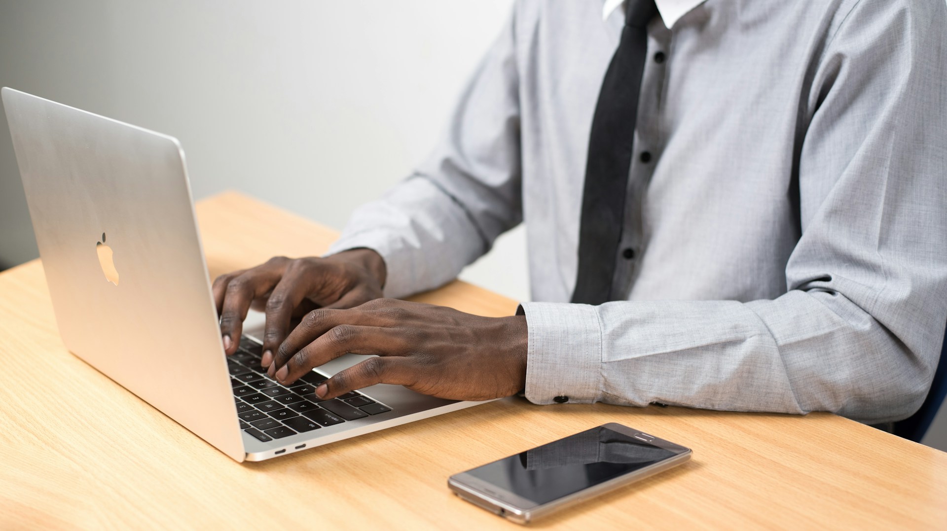 a man with a phone working at a laptop